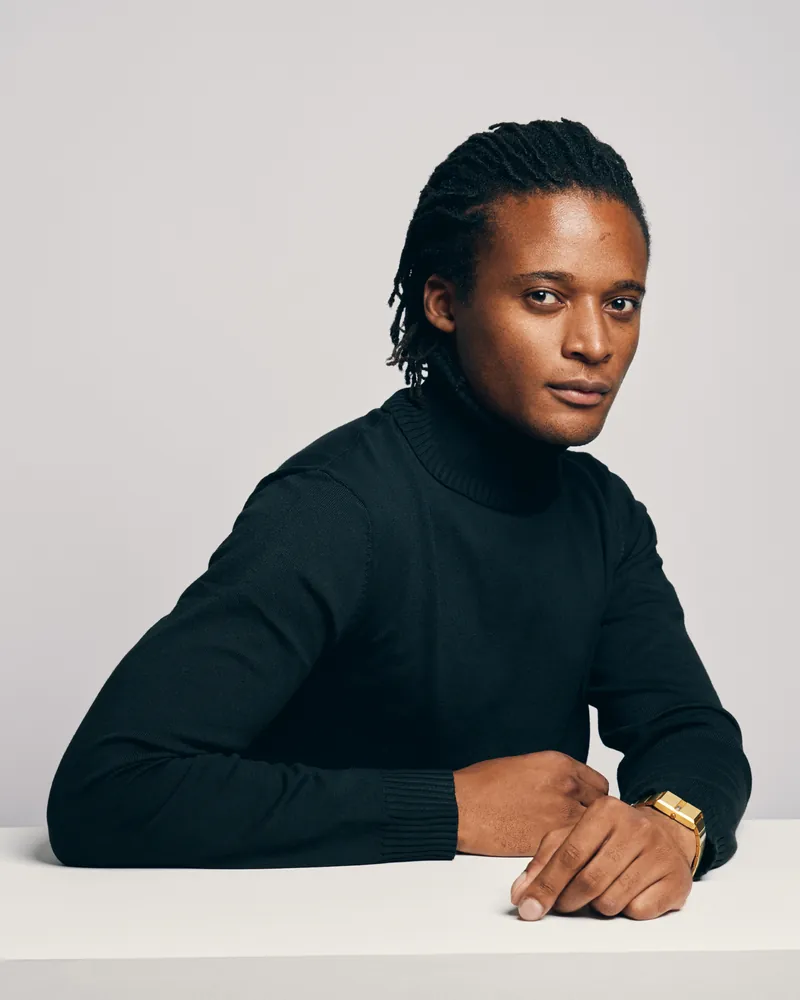 Kudzai King seated at a table in a black turtleneck.