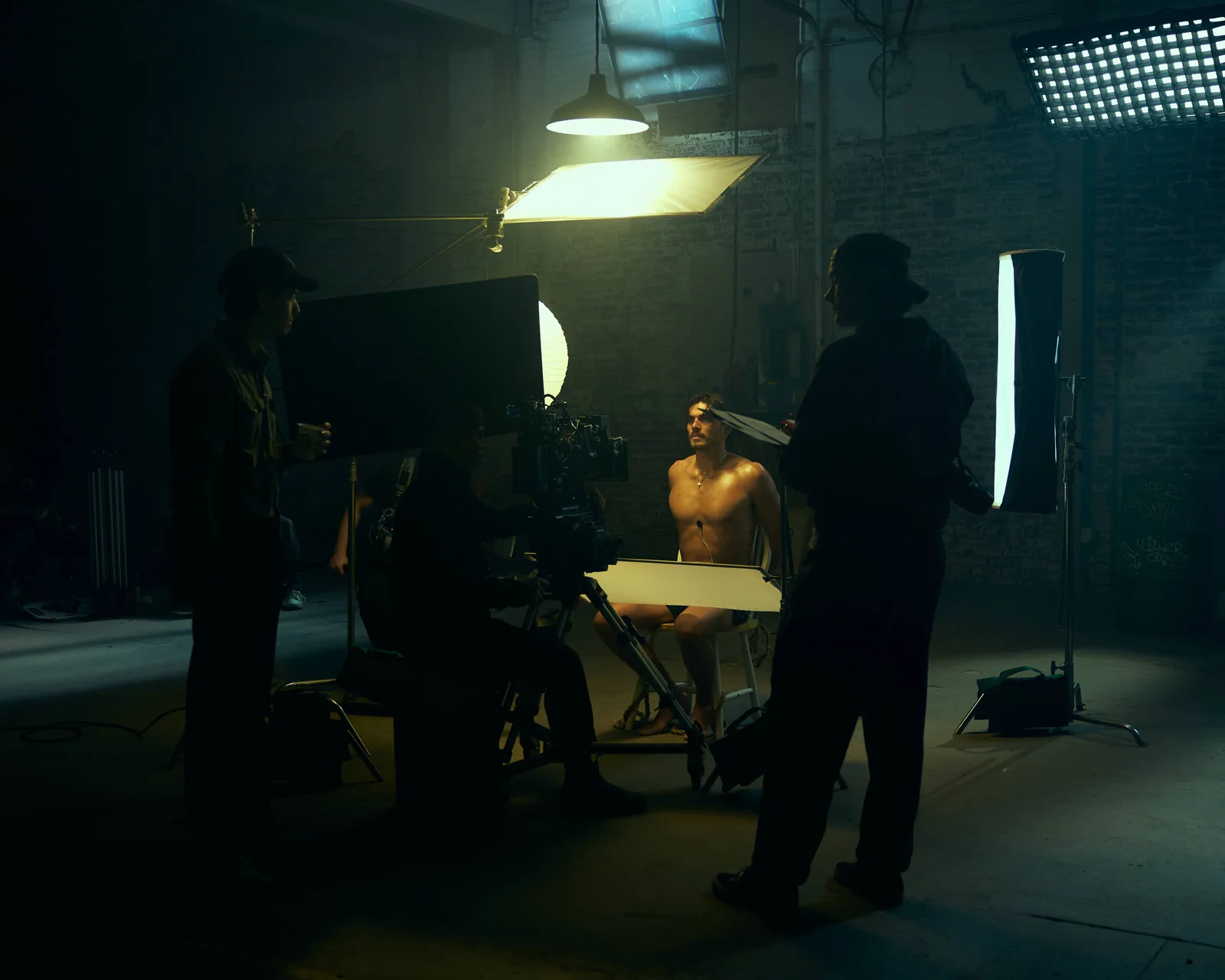Cast and crew working under large film lights in a warehouse set. The Hitman’s Dalliance.