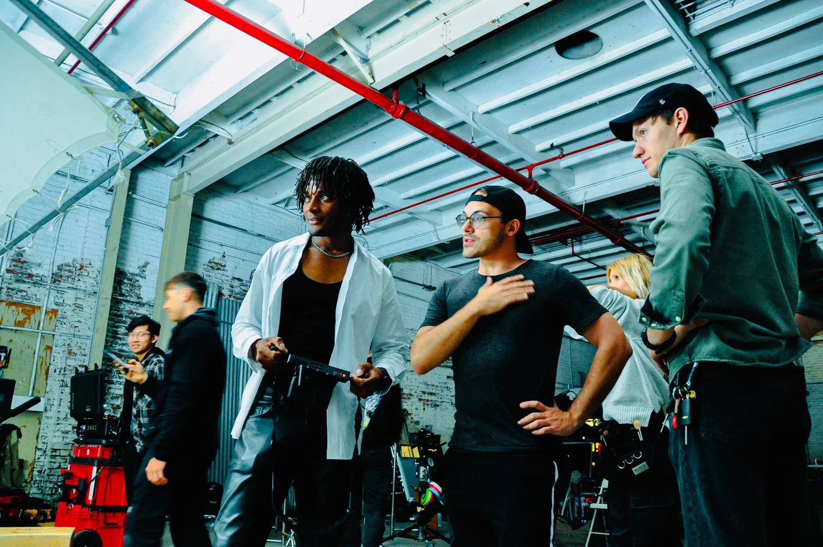 Kudzai King and crew discussing a setup beside production equipment in a daylight studio.